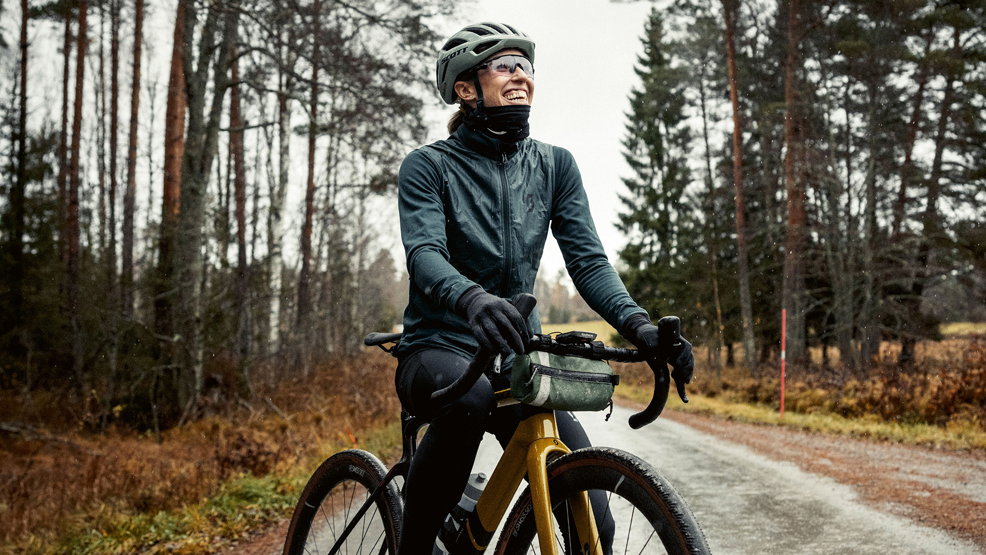 Lisa Nordén på en cykel i ett höstigt skogslandskap.