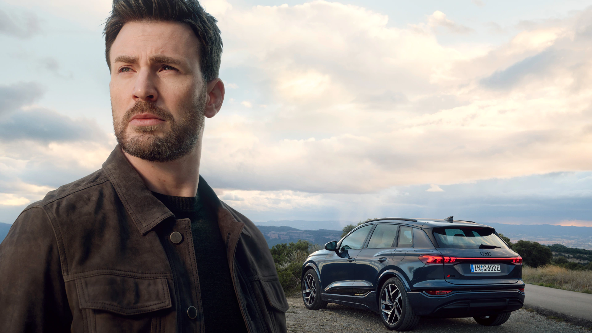 Närbild på skådespelaren Chris Evans som står med en Audi Q6 e-tron i bakgrunden.