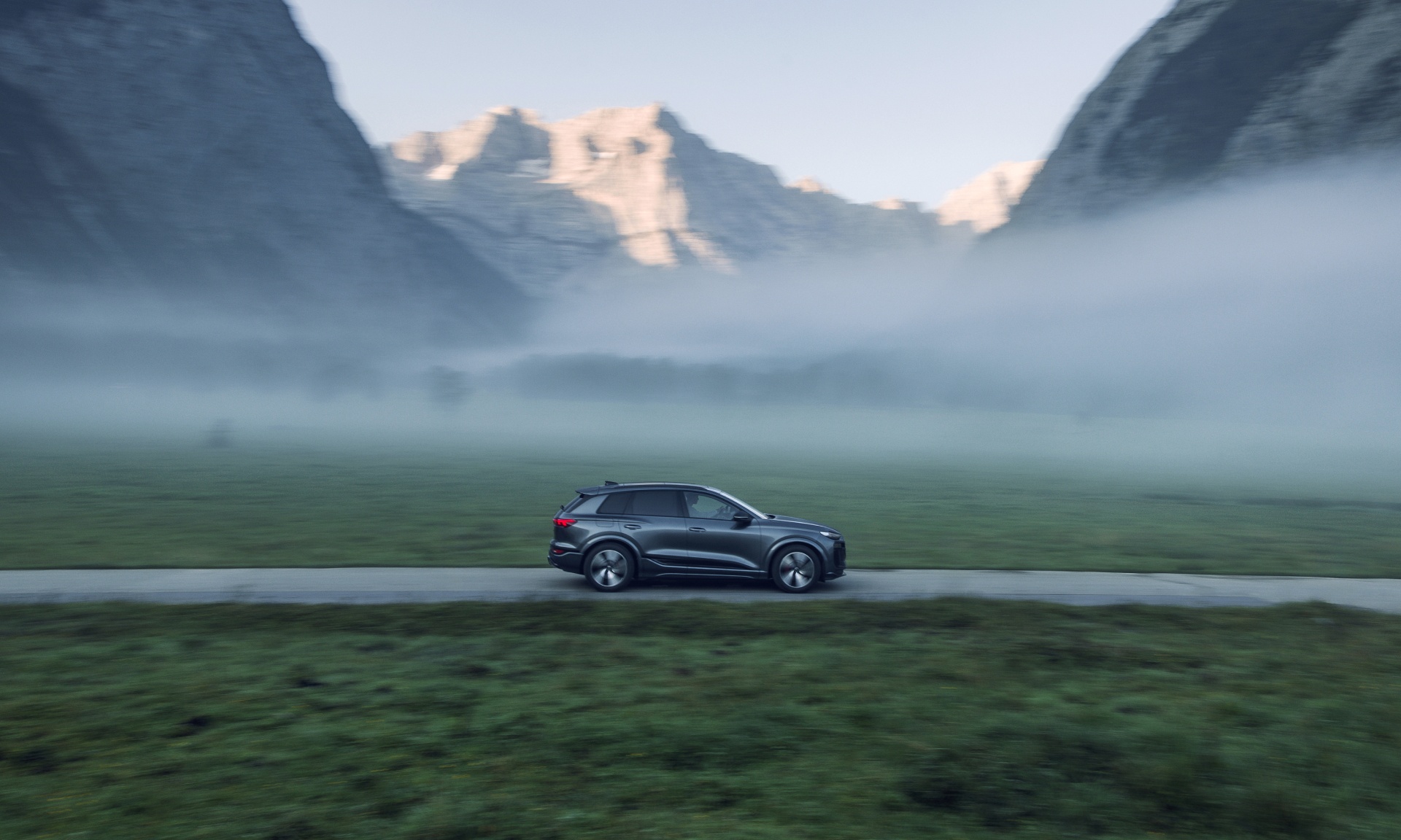 Audi Q6 e-tron som kör genom ett bergslandskap.