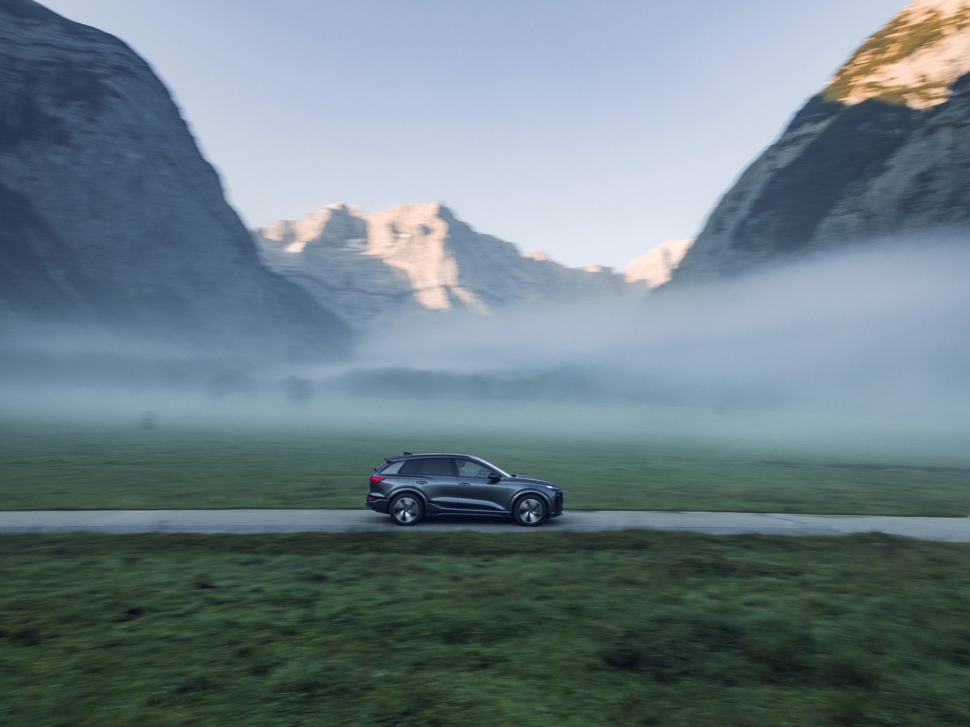 Audi Q6 e-tron som kör genom ett bergslandskap.